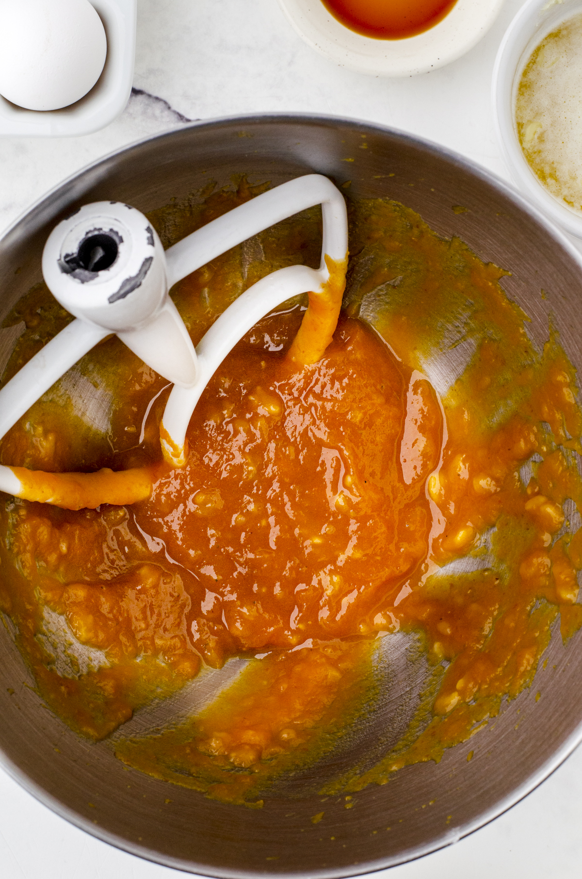 Banana, pumpkin and sugar beaten together in the bowl of a mixer for pumpkin banana muffins.