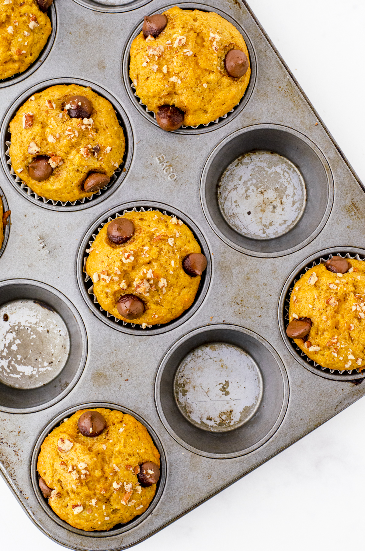 Baked pumpkin banana muffins in a muffin tin cooling off.