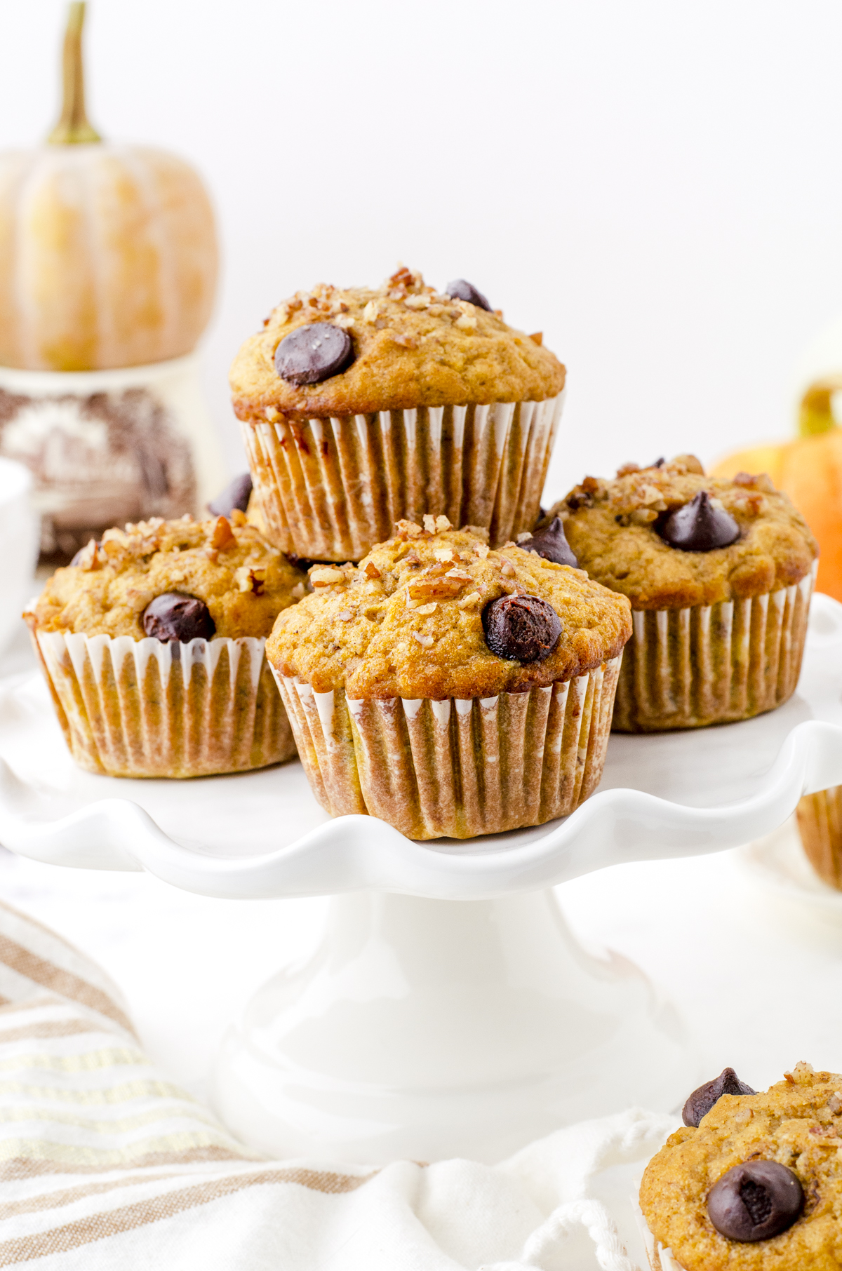 Pumpkin banana muffins stacked on a plate.
