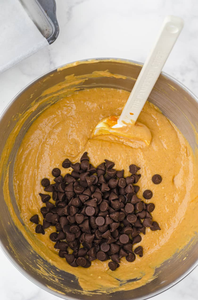 chocolate chips being stirred into pumpkin bread batter