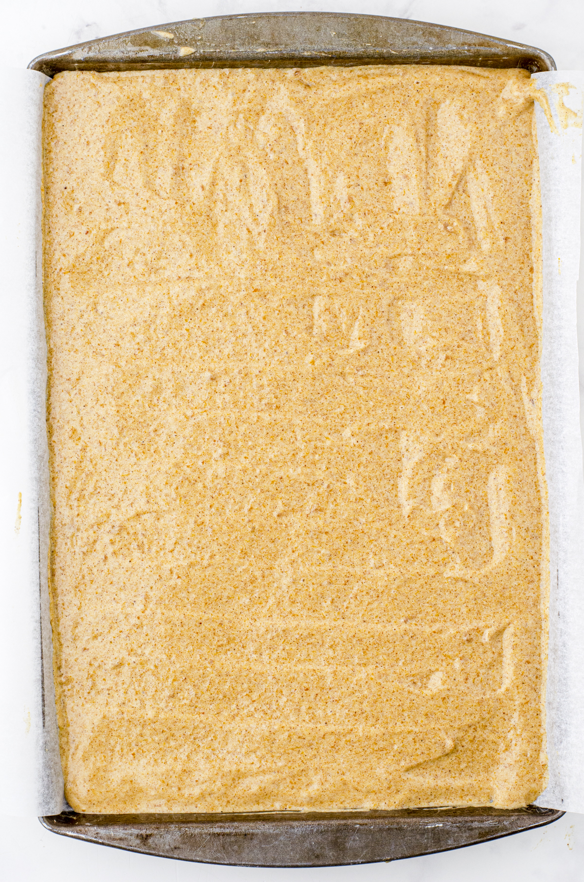 Pumpkin sponge cake spread evenly into a jelly roll sized pan that has been lined with parchment paper.