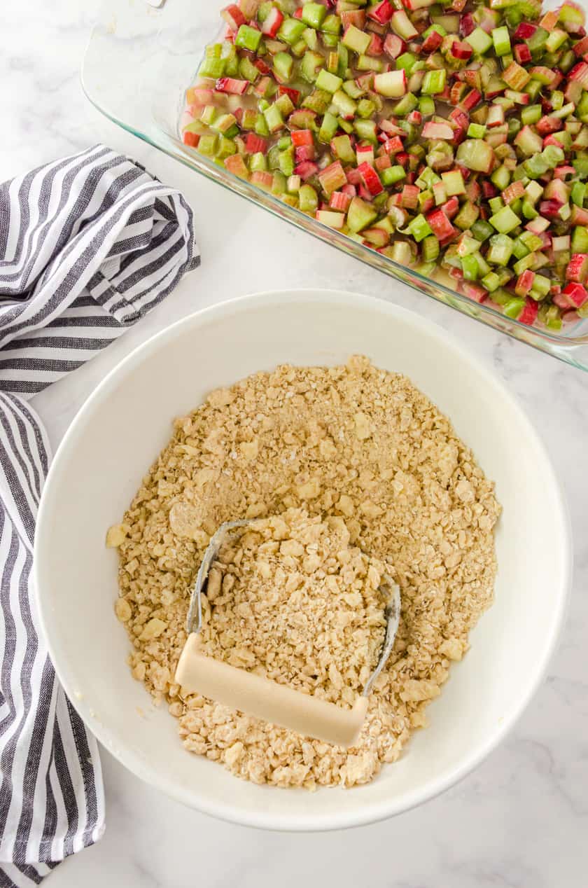 Rhubarb crisp oatmeal topping in a bowl with a pastry blender in it.