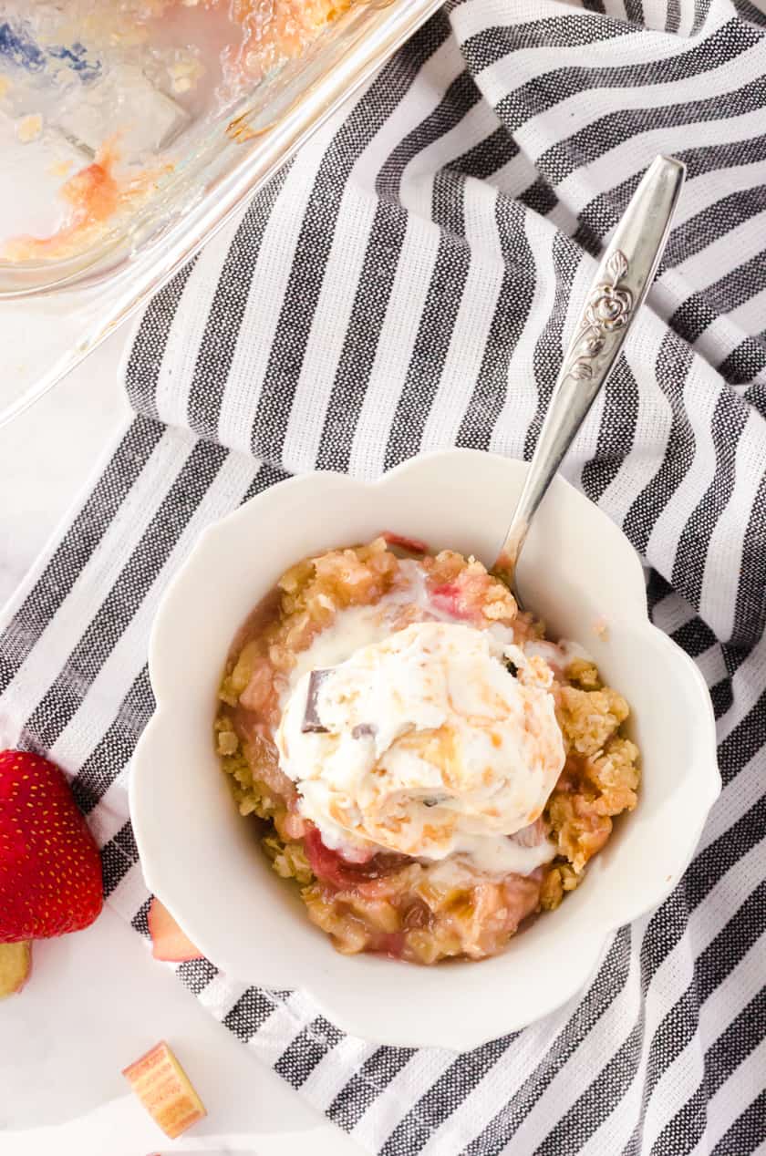 Bowl of rhubarb crisp with a scoop of vanilla ice cream on it.