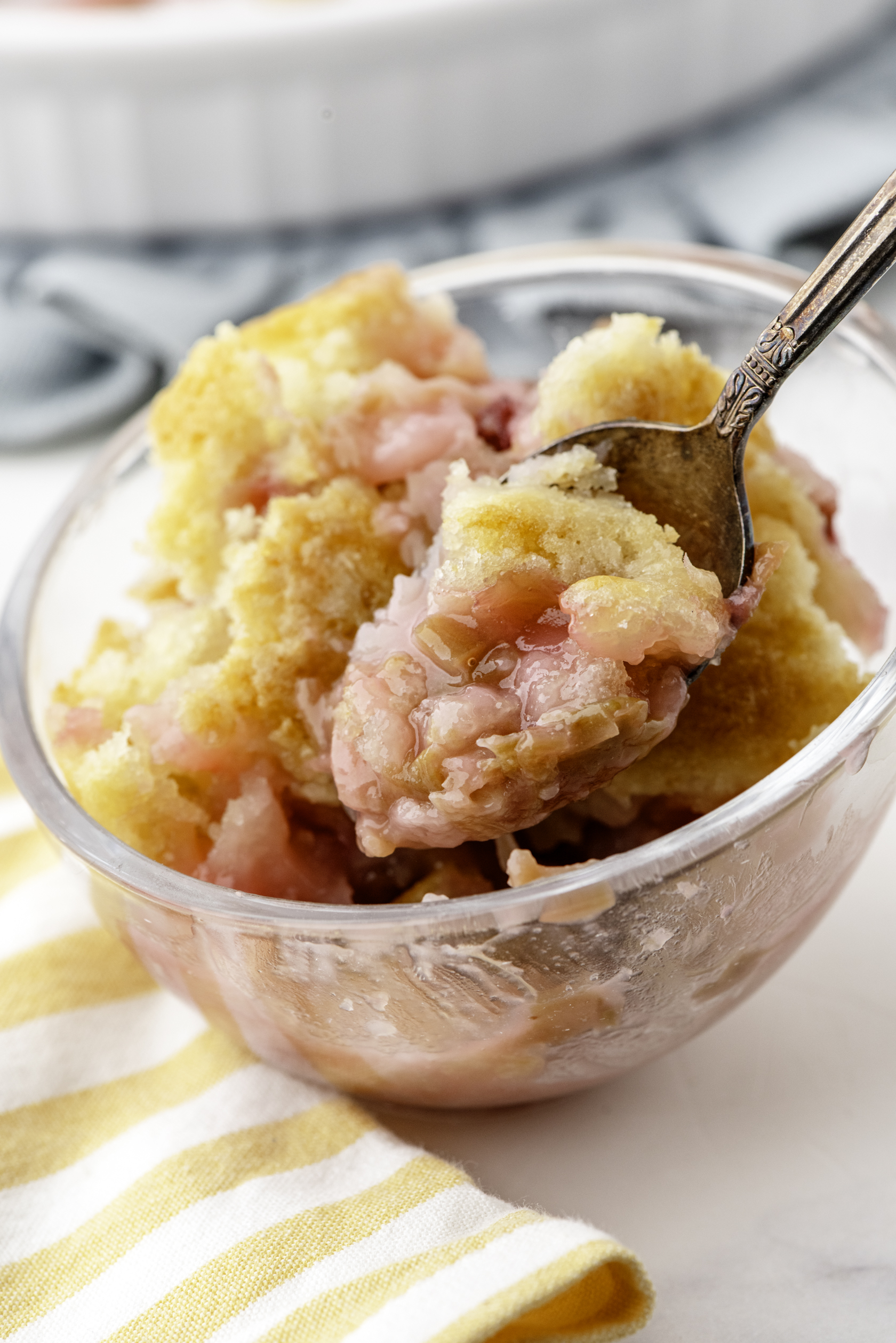 A bowl of rhubarb sticky pudding cake with a spoonful lifted out of it.