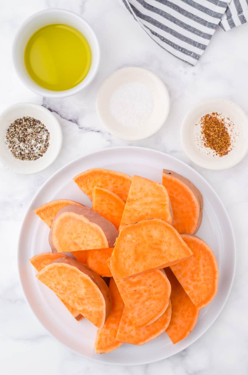 Cut giant sweet potatoe on a plate ready to be put in the microwave.