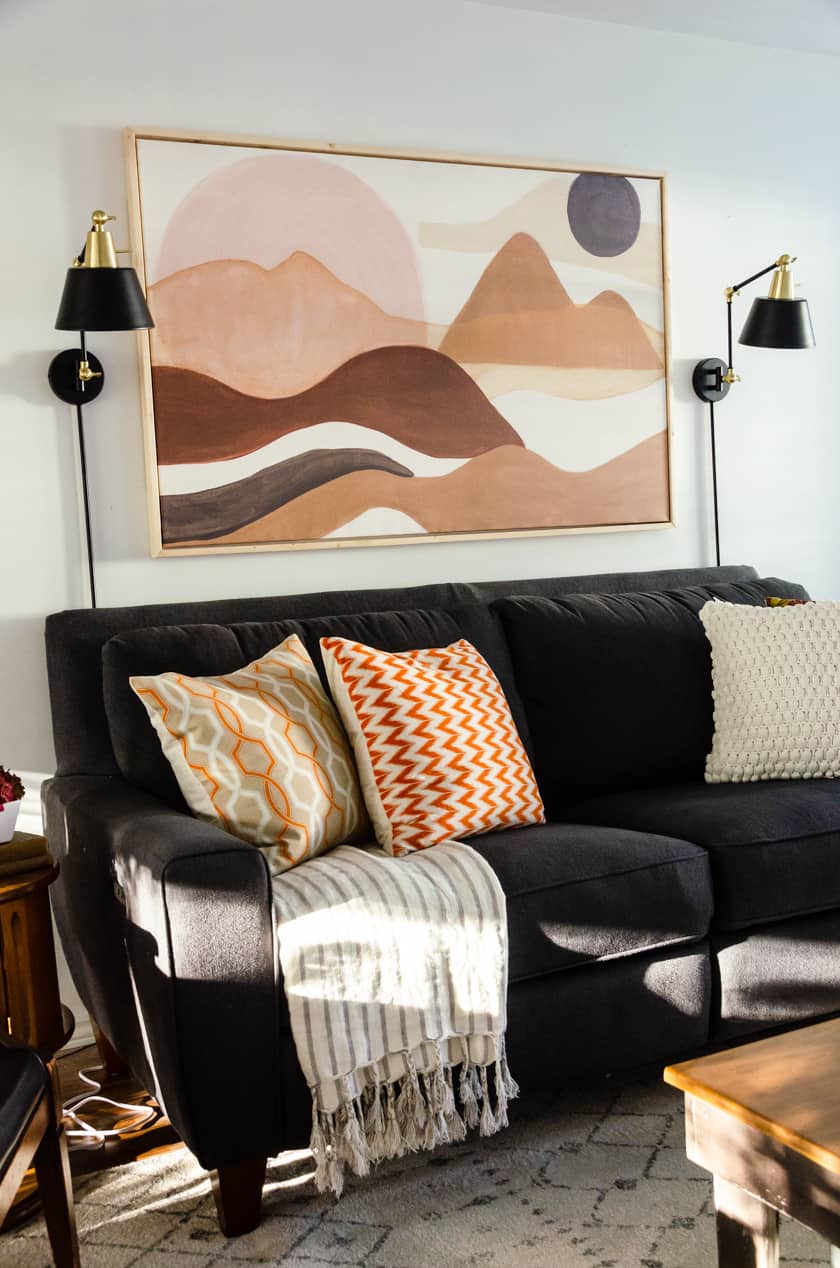 Adding a striped blanket draped on a gray Lazy-boy couch with fall colored throw pillows - an easy room decor idea for Fall!