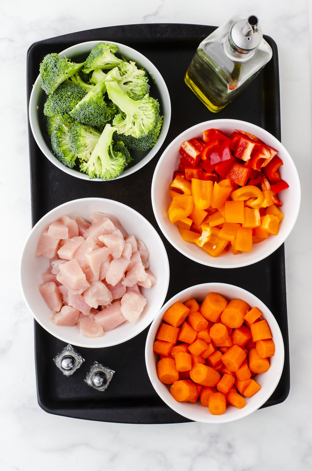 Ingredients for sheet pan chicken and veggies with broccoli, peppers, and carrots.