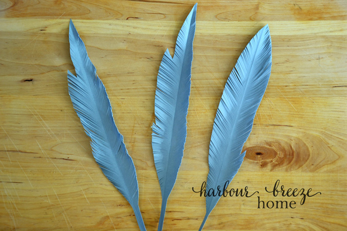 Paper feather shapes cut out of gray cardstock with tiny cuts around the edges to resemble the look of a feather.