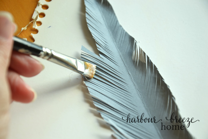 Painting the edges of a paper feather with white acrylic paint
