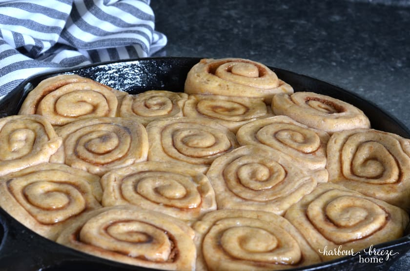 Caramel cinnamon rolls in dough form arranged in a cast iron skillet when they have risen to double their size and are ready to put in the oven.
