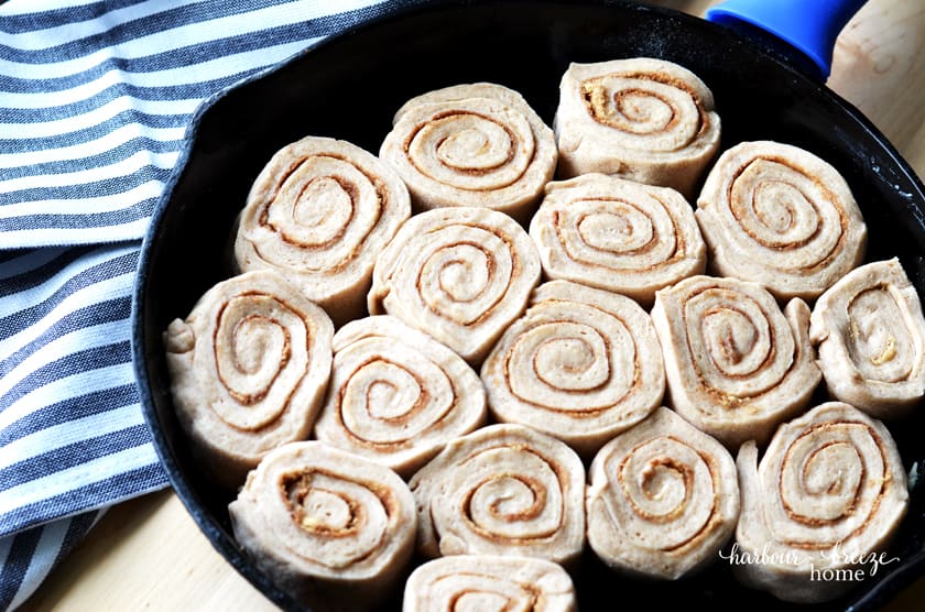 Caramel cinnamon rolls in dough form arranged in a cast iron skillet
