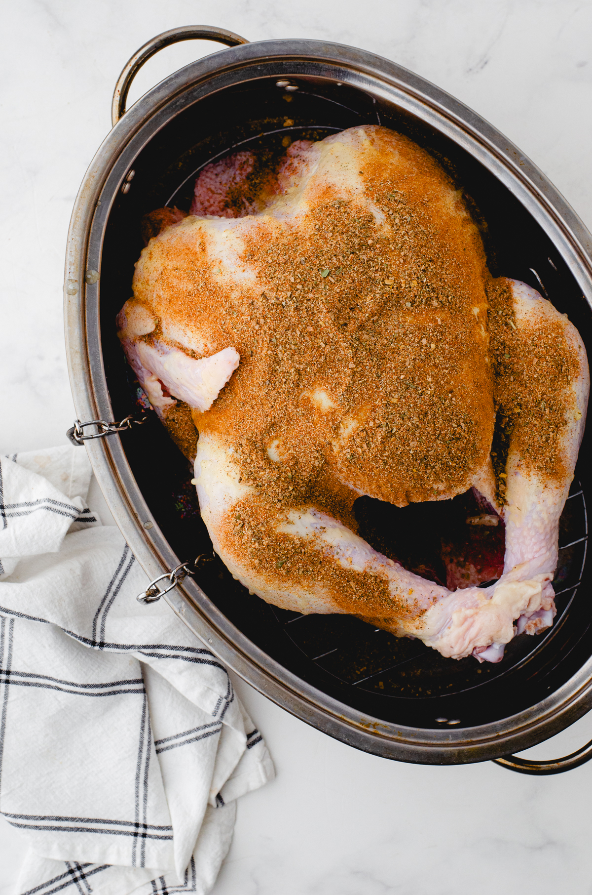 Whole Turkey in roasting pan with spice rub on it.