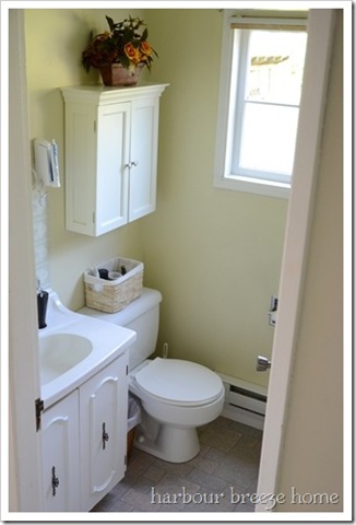 White cabinet about a toilet in a small bathroom.