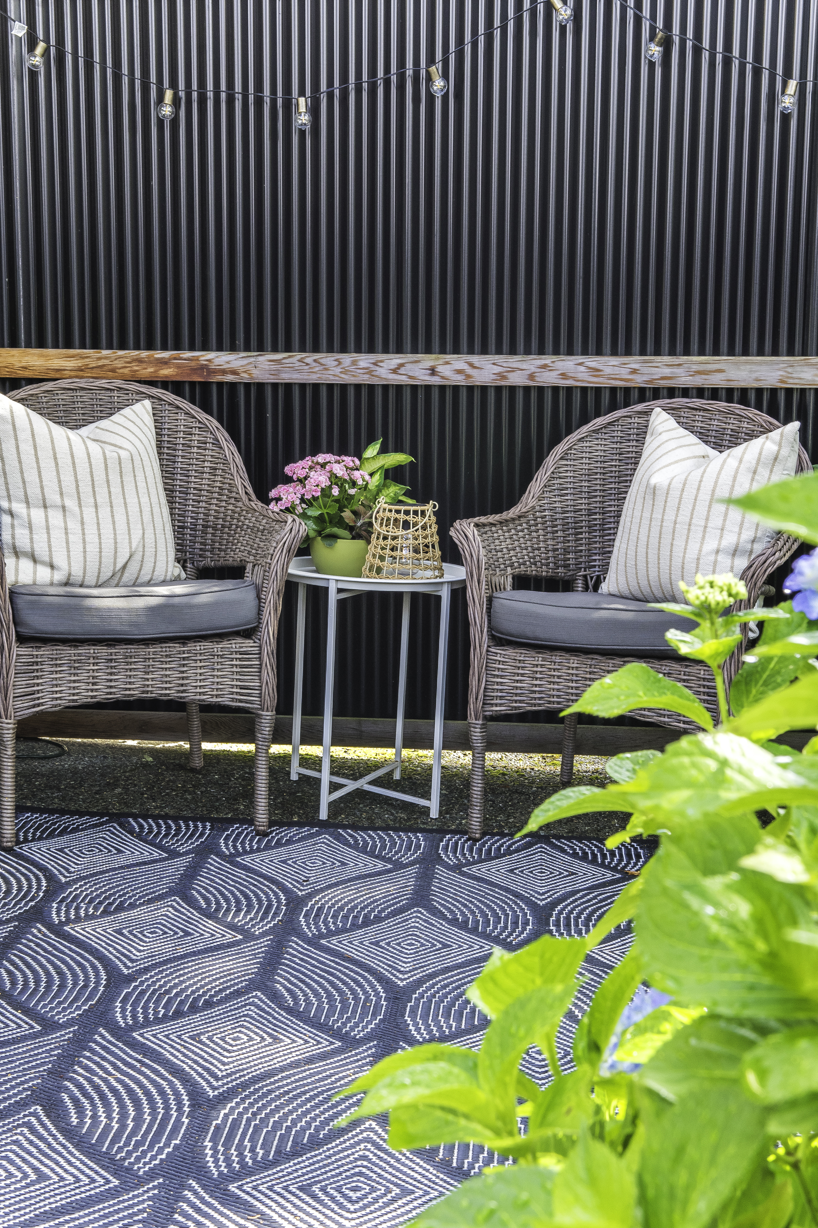2 patio chairs on a patio with a side table between them.