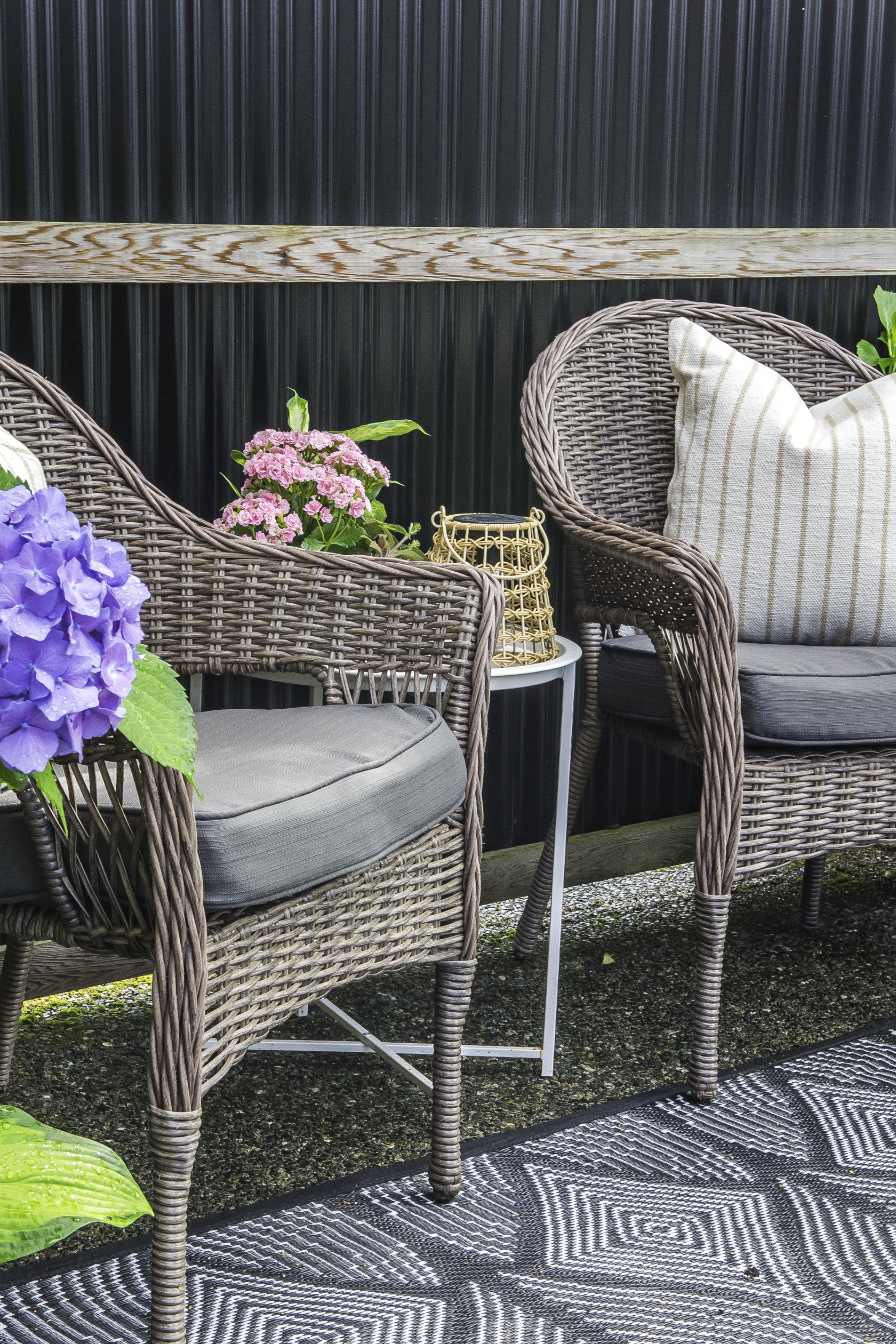 Two patio chairs with cushions with a side table between.