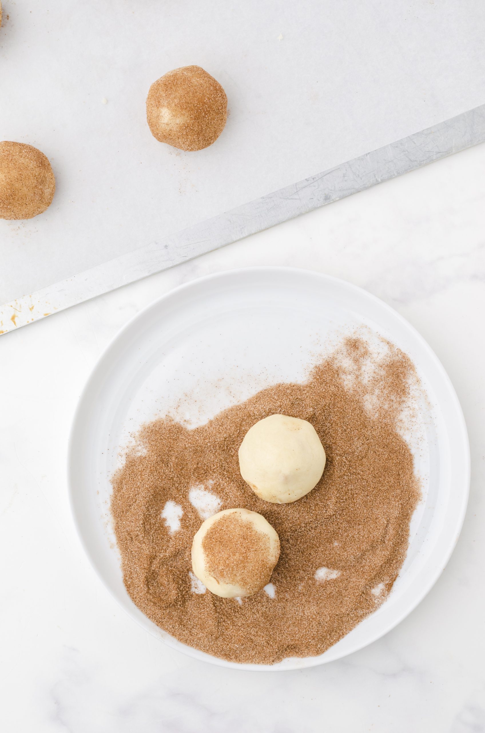 snickerdoodle caramel bits cookies being rolled in cinnamon sugar