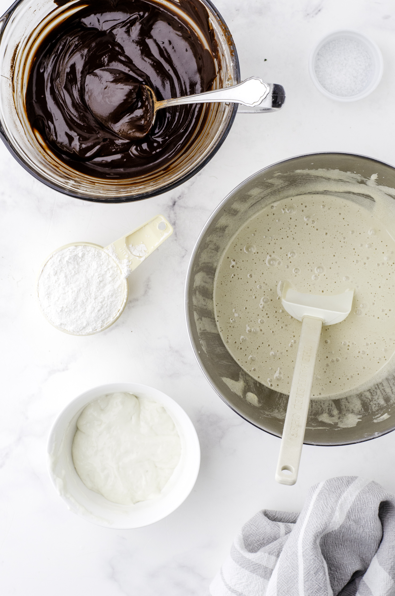 A microwave safe bowl with the chocolate mixture melted and stirred until smooth, and the bowl of a stand mixer with a mixture of beaten eggs and sugar.