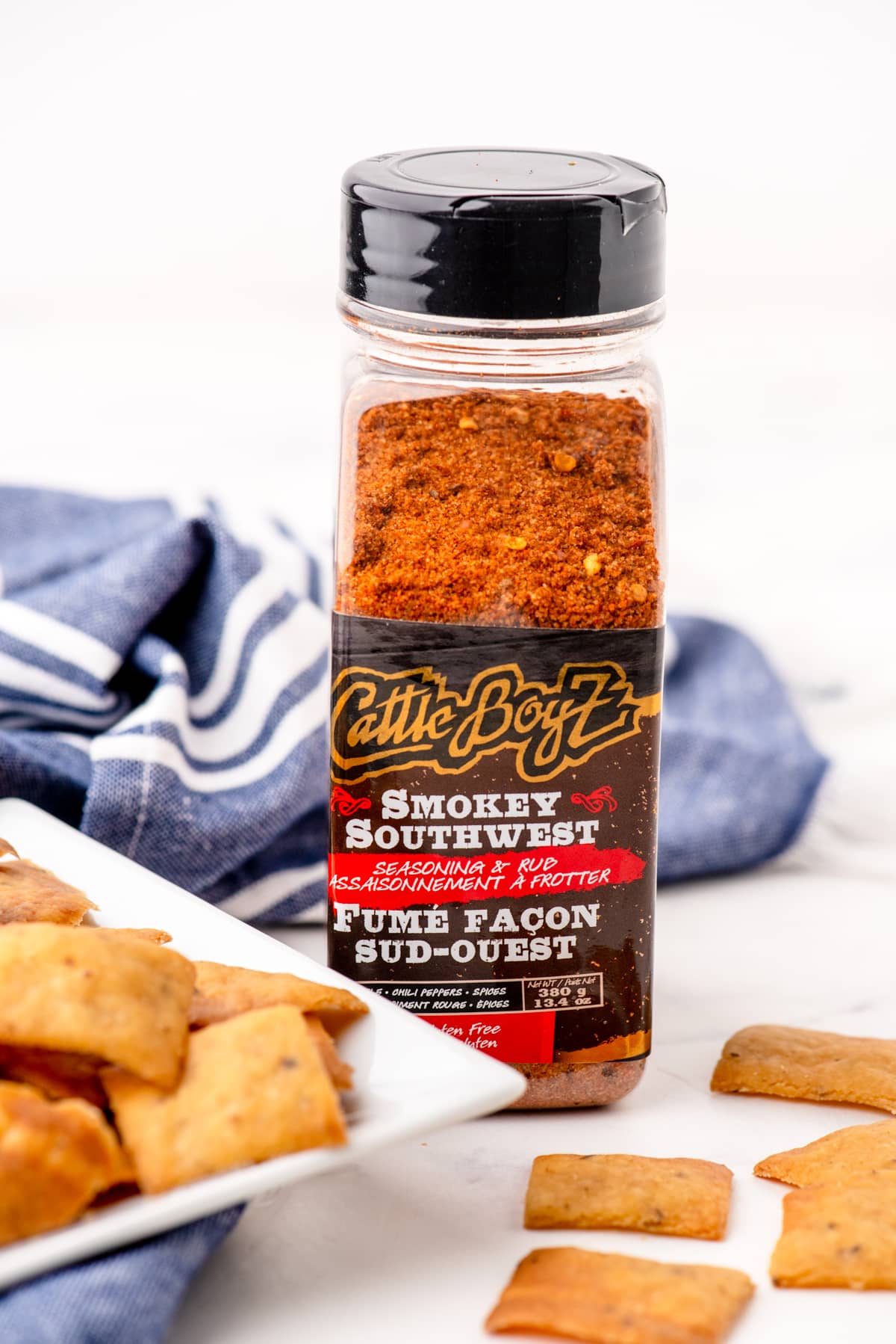A container of smokey southwest seasoning beside a plate of sourdough chips.