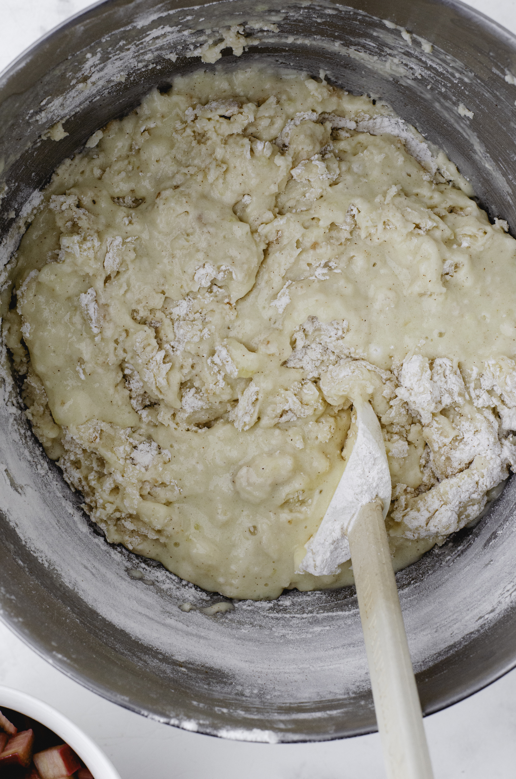Rhubarb muffin batter being stirred together with a rubber spatula.