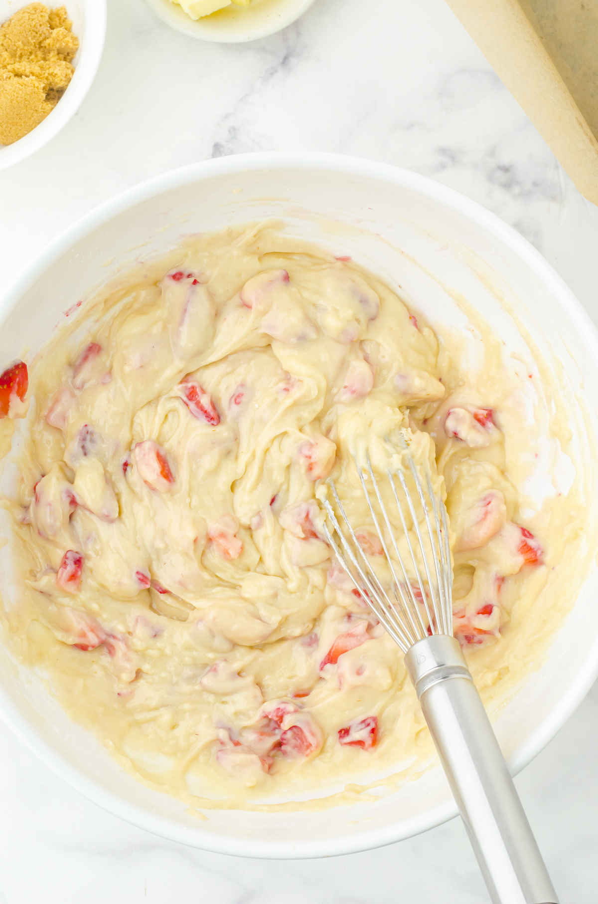 Fresh strawberries folded into quick bread batter in a medium sized bowl