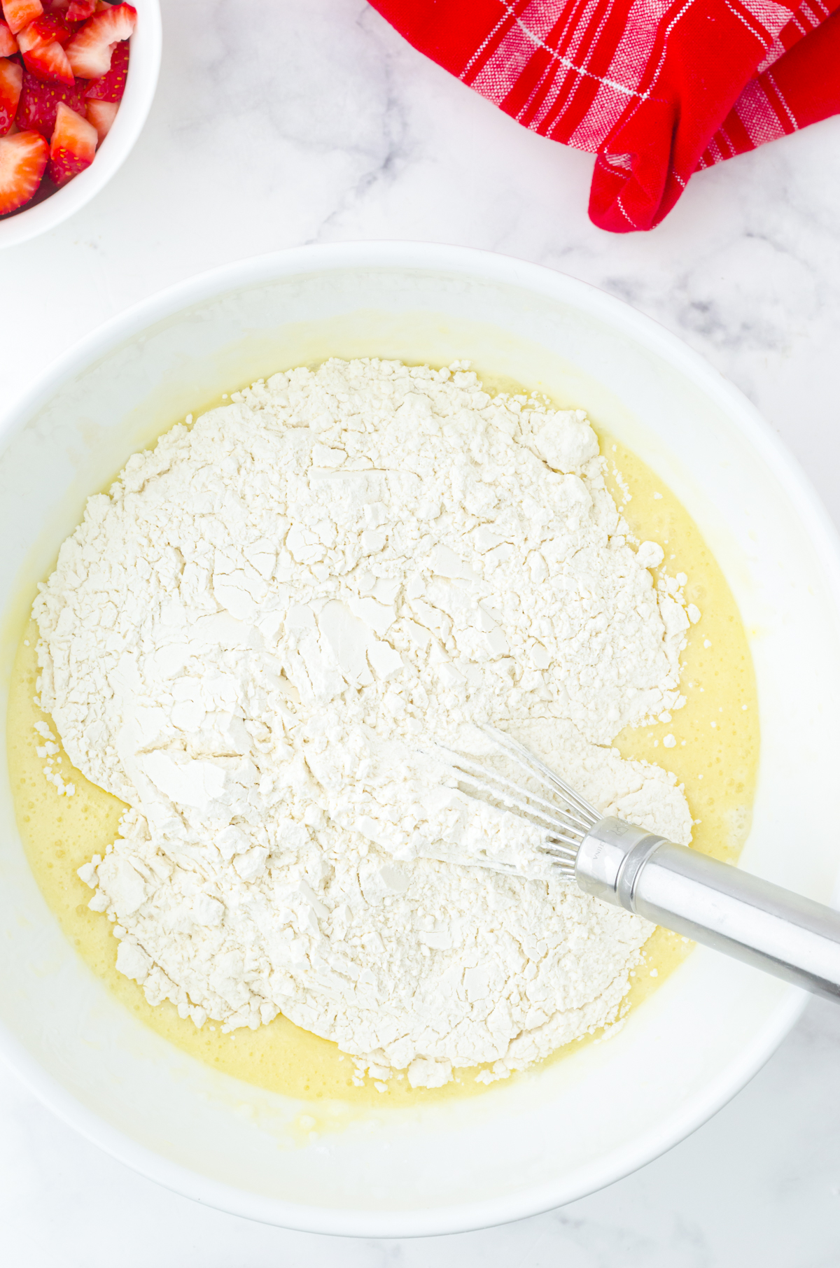 Flour being added to the strawberry muffin batter.