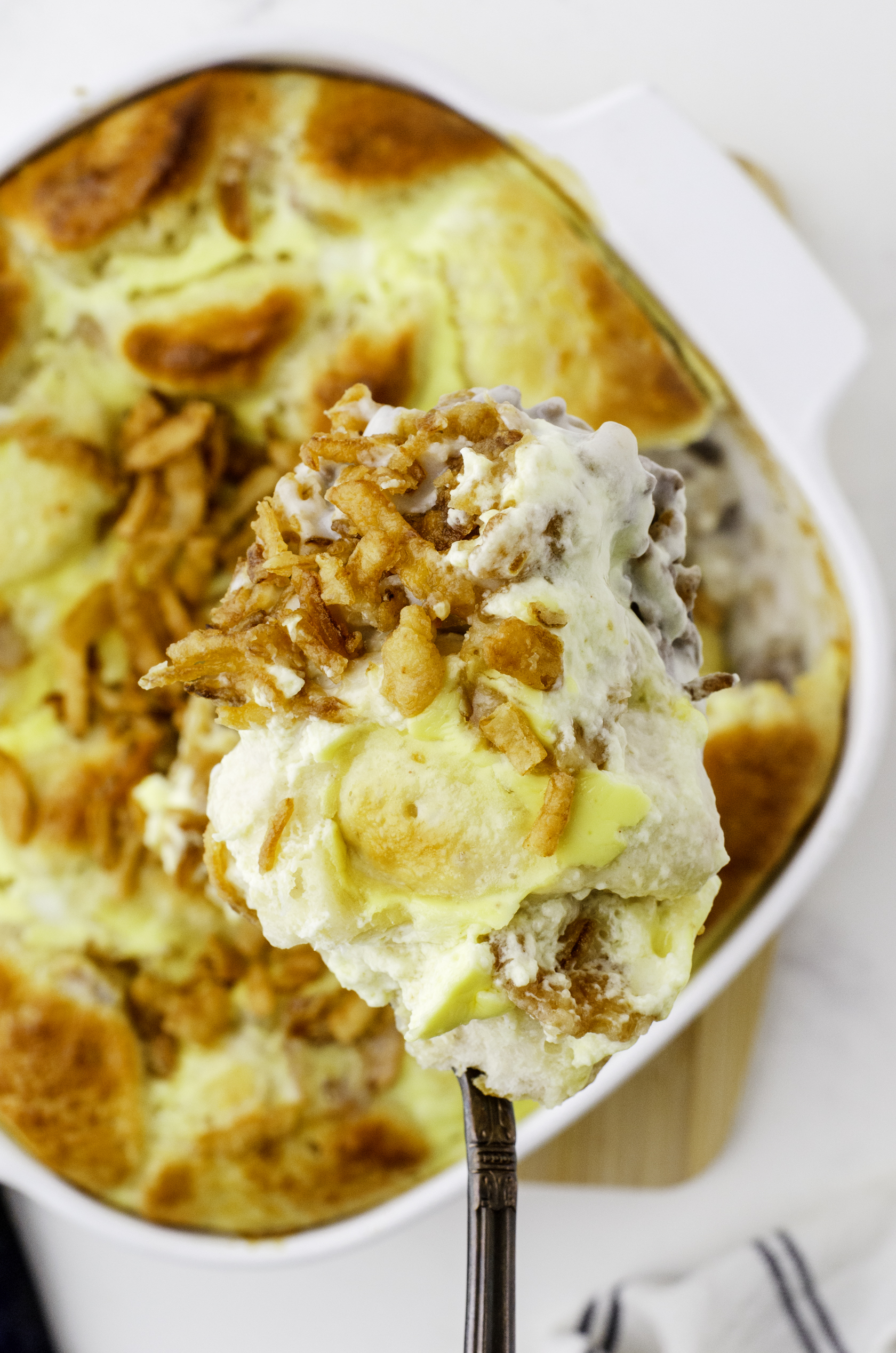 A serving spoon full of hamburger stroganaff casserole.