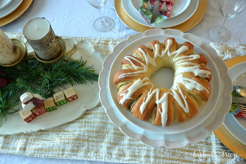 Swedish Tea ring on a white cake plate sitting in the middle of a table set for dinner