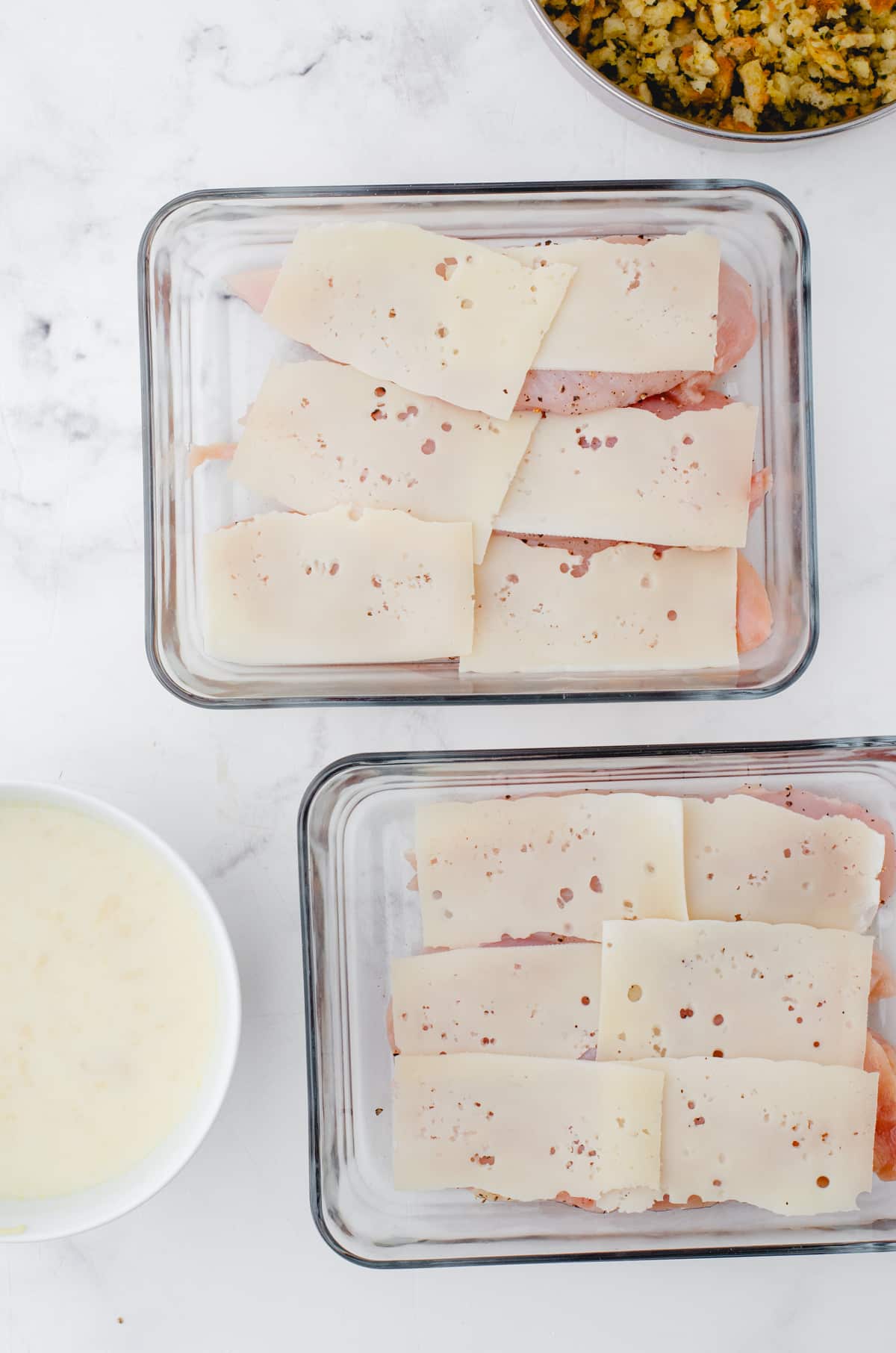 Swiss cheese layered on chicken breasts in a casserole dish.