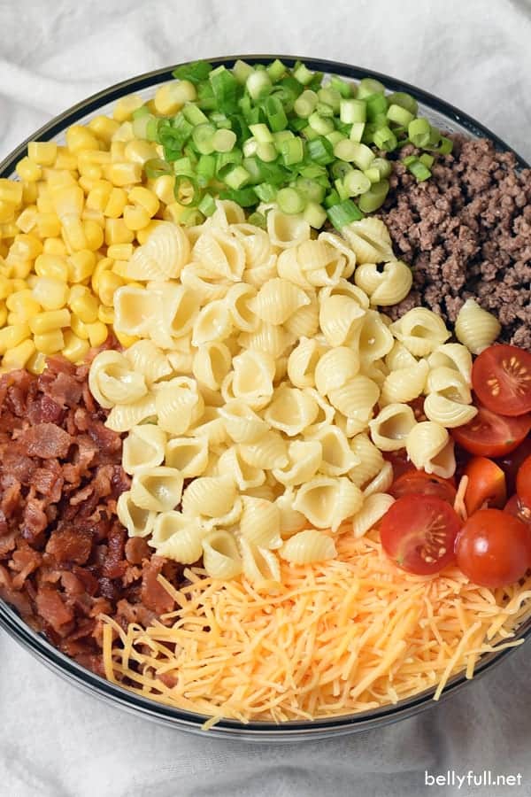 Pasta salad ingredients in a bowl ready to stir
