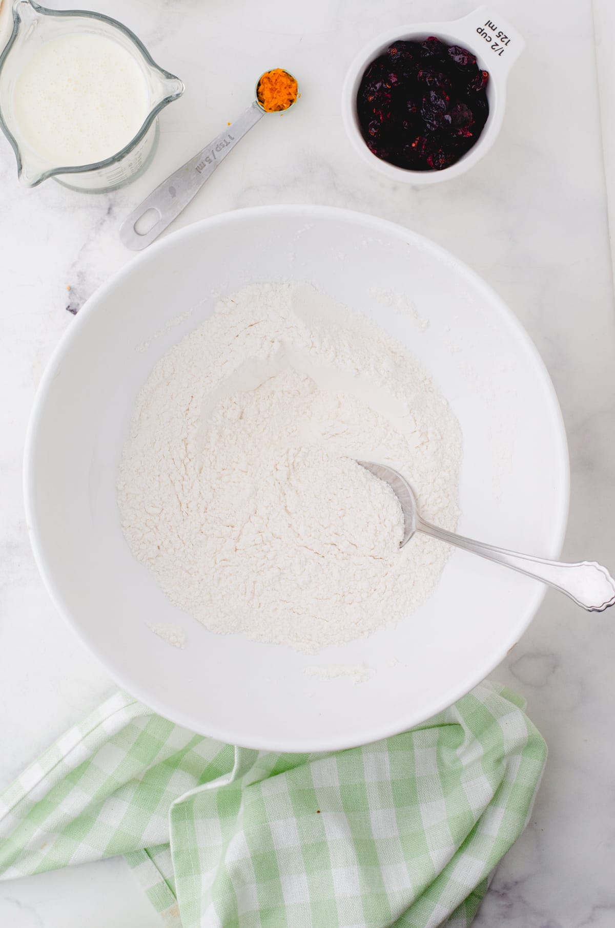 Dry ingredients for cream scones in a mixing bowl being stirred together.