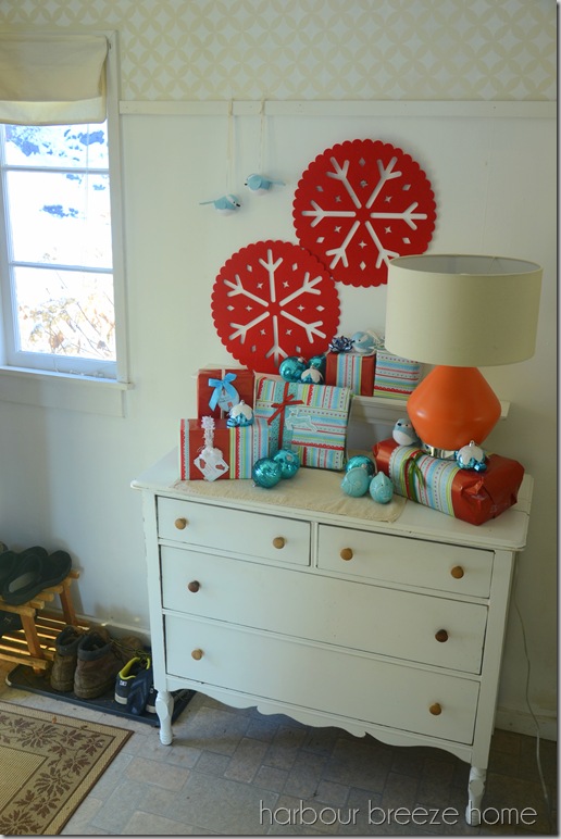 dresser used as an entryway table decorated for Christmas with wrapped gifts