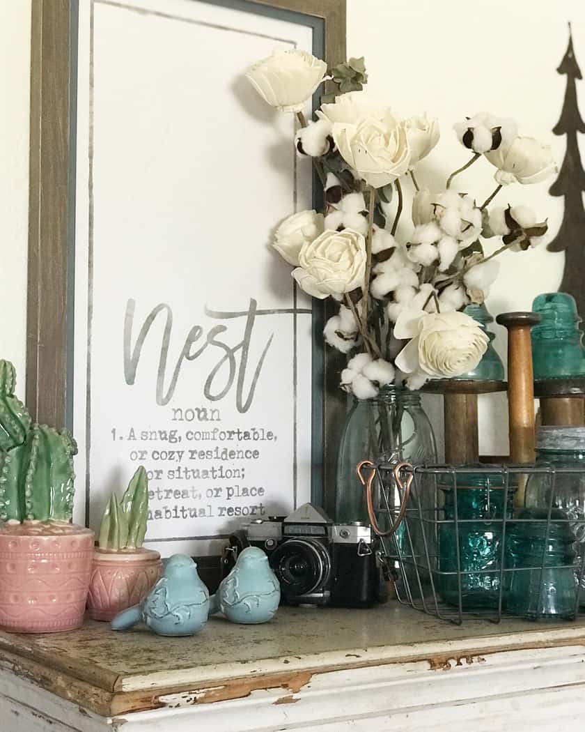 A rustic sign with a bouquet of white flowers in front of it sitting on a shelf