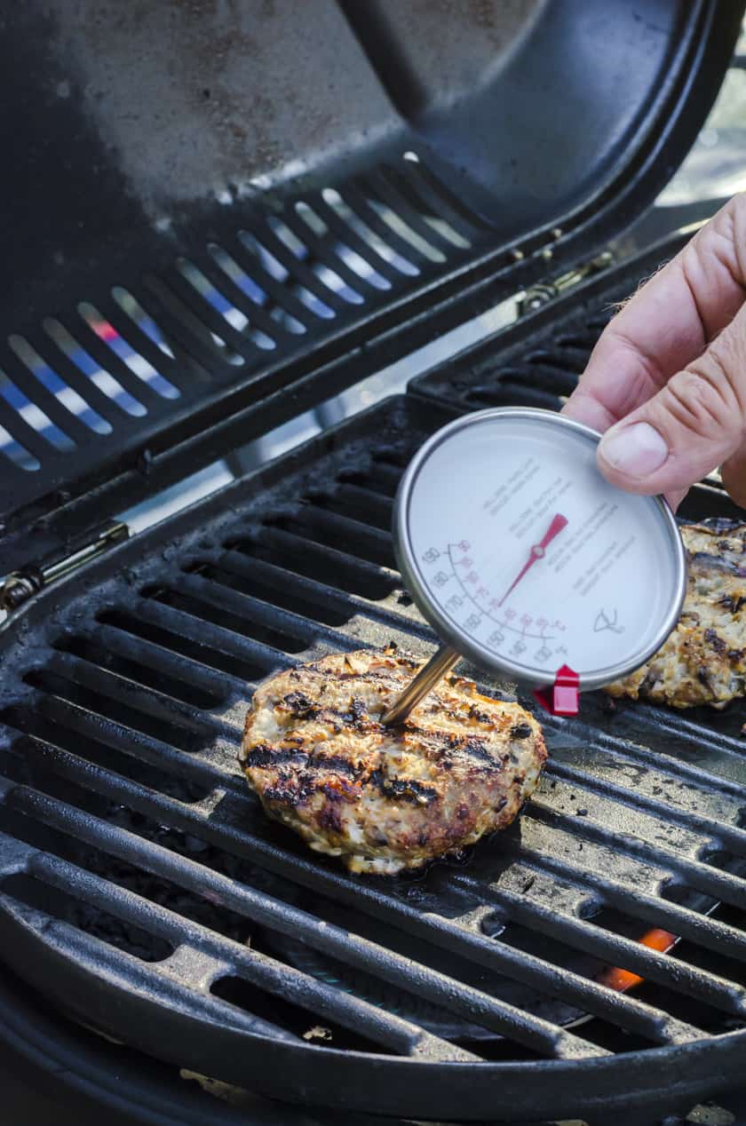 a food thermometer being places in the center of a turkey burger.