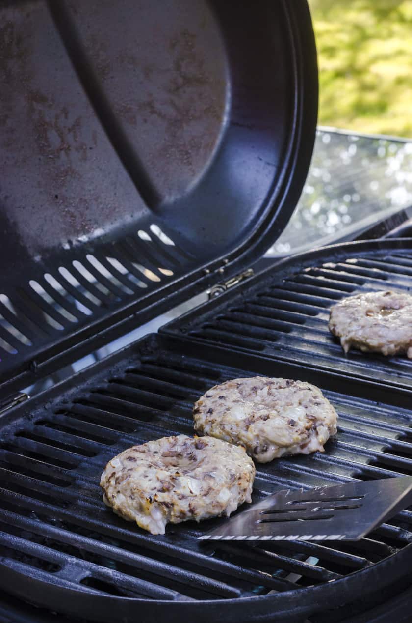 A homemade turkey burger being flipped with a large barbecue flipper.