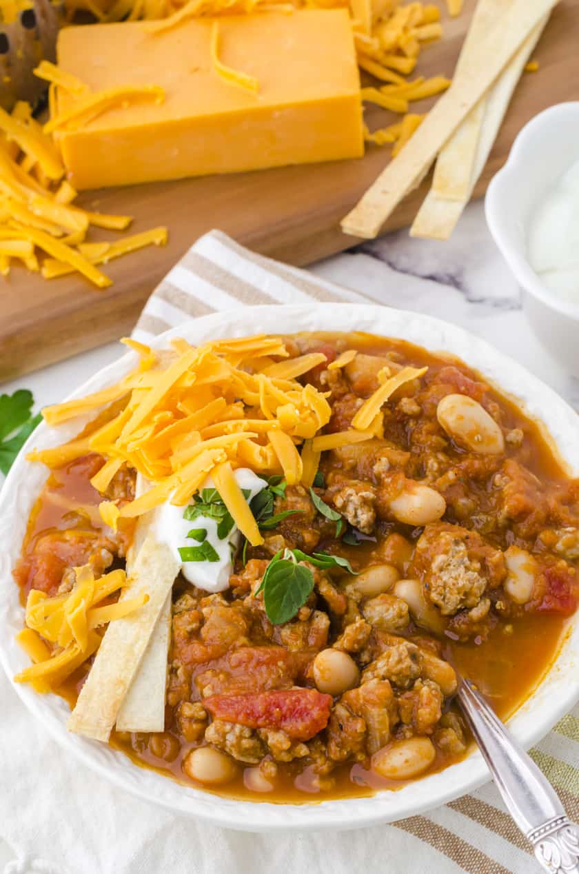 A bowl of turkey pumpkin chili with toppings.