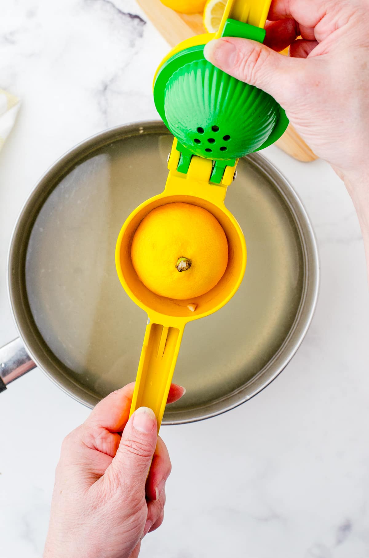 Lemon in lemon juicer over a pot of water for tumeric tea.