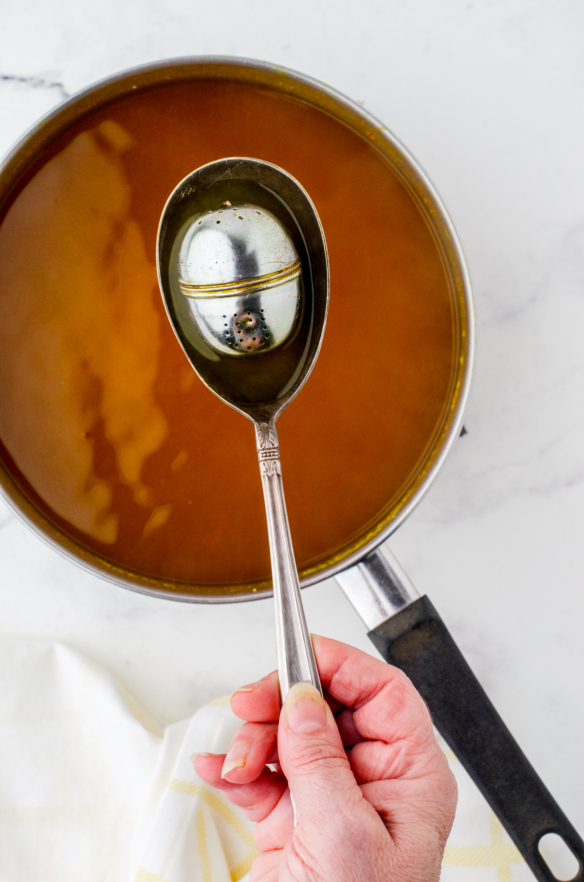 Tea infuser being removed from tumeric tea concentrate.