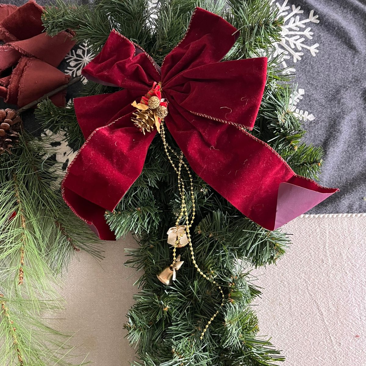 An outdated Christmas swag with old dusty ribbon and tacky gold beads and bells