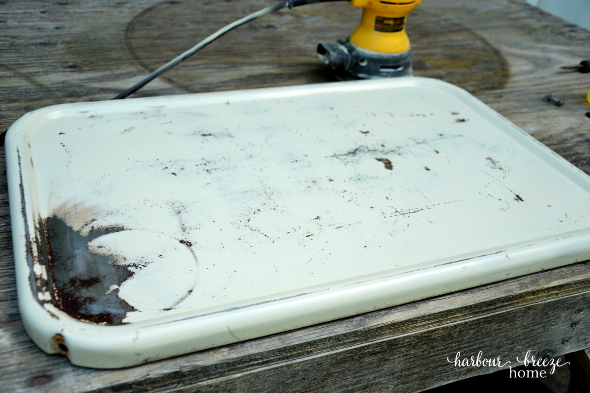 The sanded shelf of an old metal cart before it gets spray painted.