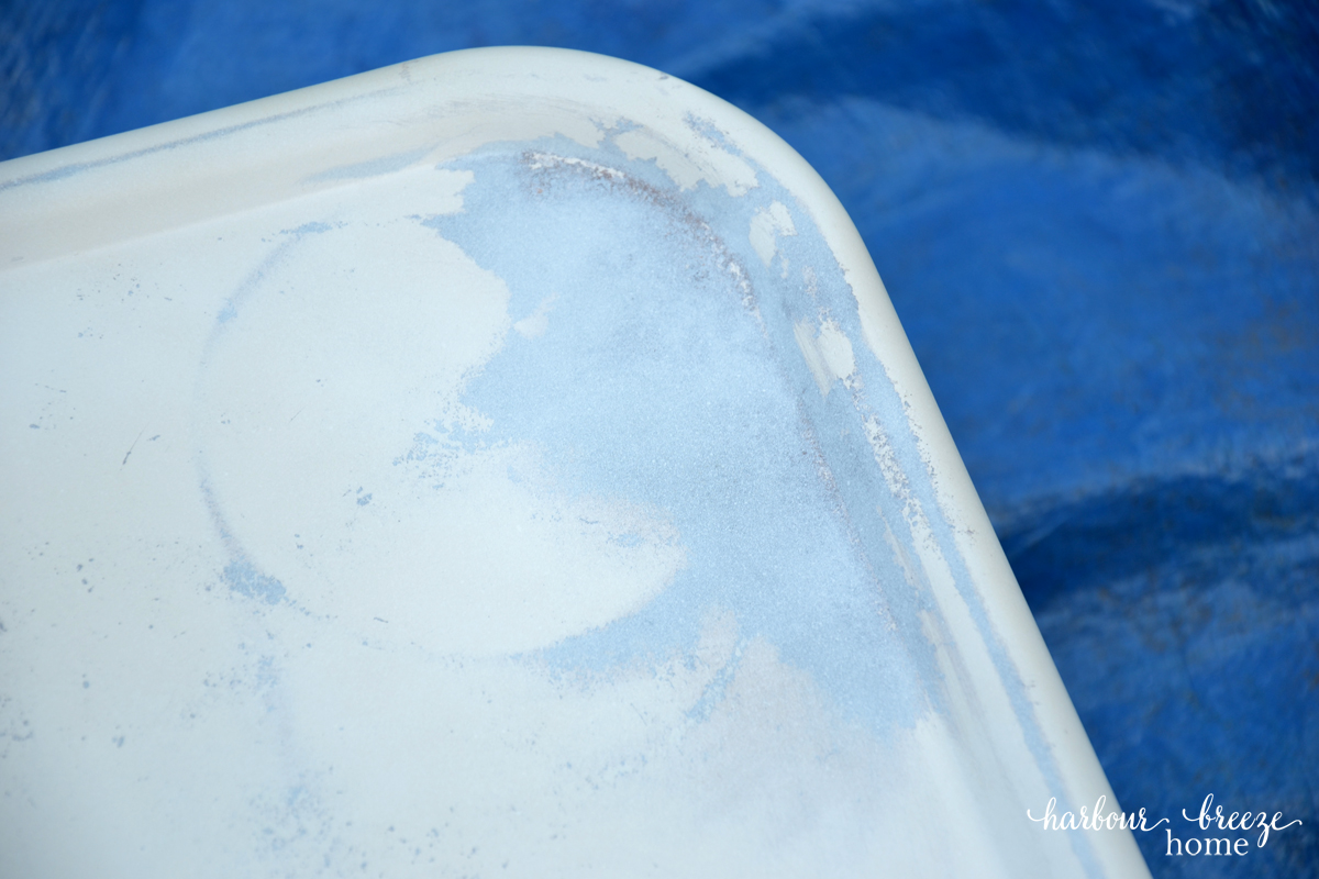 A tray of a metal cart that has been primed with spray paint specifically made for rusty metal