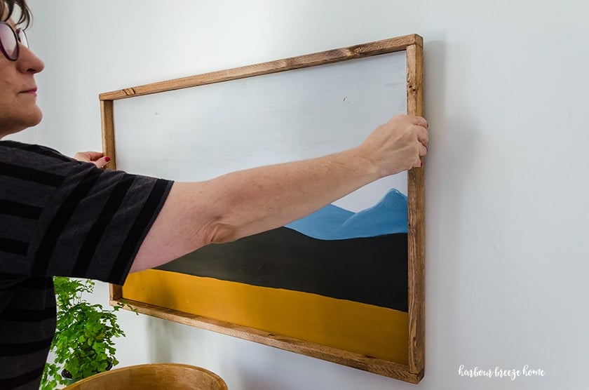woman hanging a picture on the wall