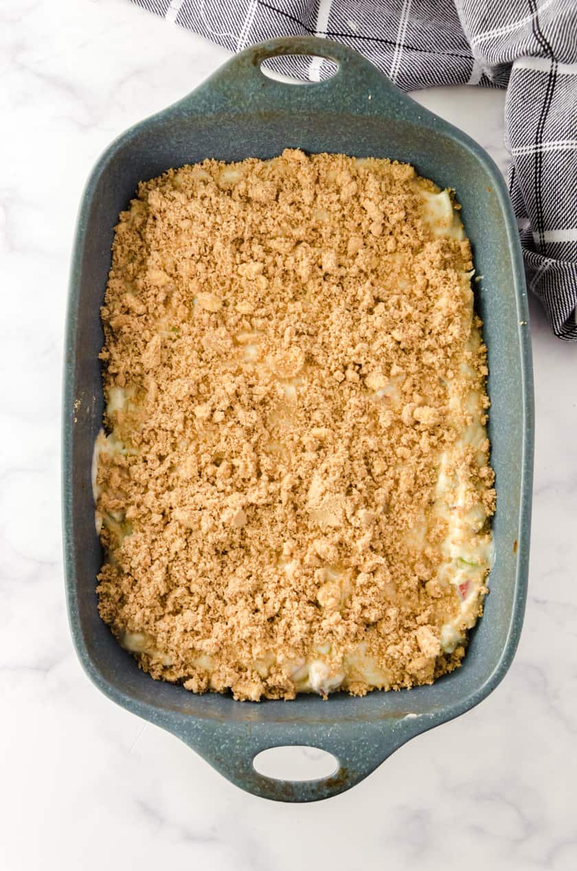coffee cake topping sprinkled on top of rhubarb coffee cake batter in a 9x13 pan