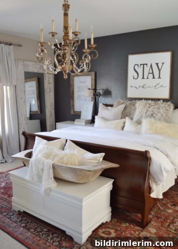 Stylish Modern Farmhouse Bedroom Ideas 7 A farmhouse style bedroom with a black feature wall with a bed with a wooden frame against it with white bedding.