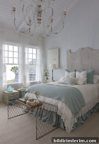 Stylish Modern Farmhouse Bedroom Ideas 8 A farmhouse bedroom with a vaulted ceiling, large chandilier, and a bed with a white washed headboard, & white bedding with light blue accents.