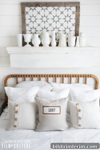 Stylish Modern Farmhouse Bedroom Ideas 9 A farmhouse bedfroom with a wooden bedframe with a shelf above it with white pitchers and a sign.