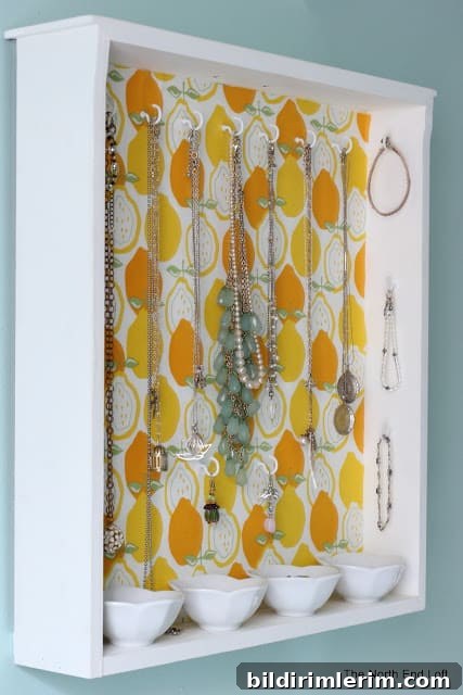 a simple drawer is repurposed into a jewelry holder by adding cup hooks on the back and sides.
