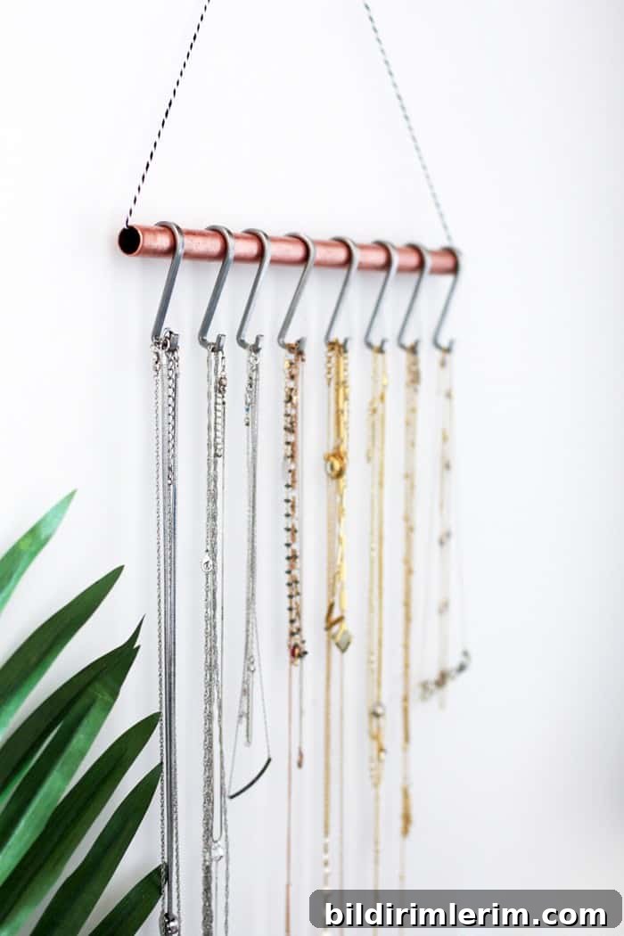 Rope strung through a copper pipe and hung on the wall becomes a beautiful organizer for necklaces when s- hooks are hung over it.