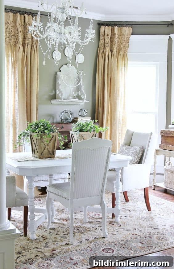 Modern Farmhouse Bloggers to Follow for Home Design 10 Dining Room with beaded chandelier, burlap curtains, and white table with wood buckets of greenery on it