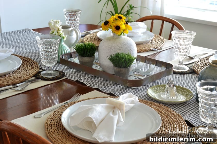 a table set with yellow flowers on a metal tray and white dishes