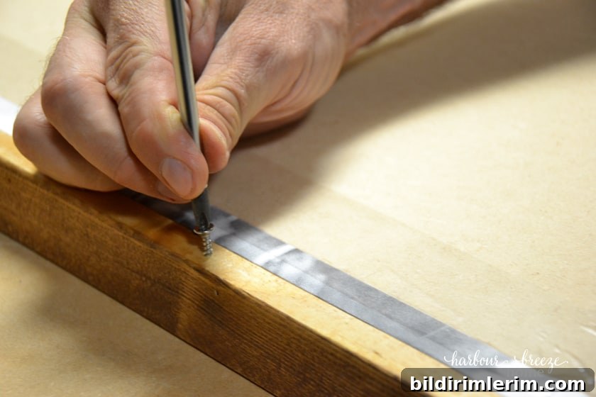 How to Frame and Engineer Print | A Budget Friendly Large Wall Art Project close up of a screw being placed in the side of a frame
